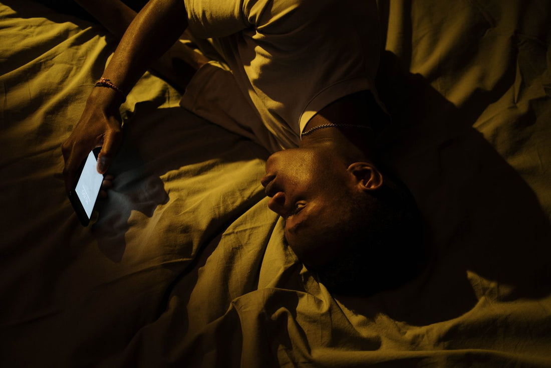 A man relaxing in bed at night looking at his phone